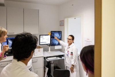 Ärztin zeigt auf einem Bildschirm ein Mammografiebild einer Brust