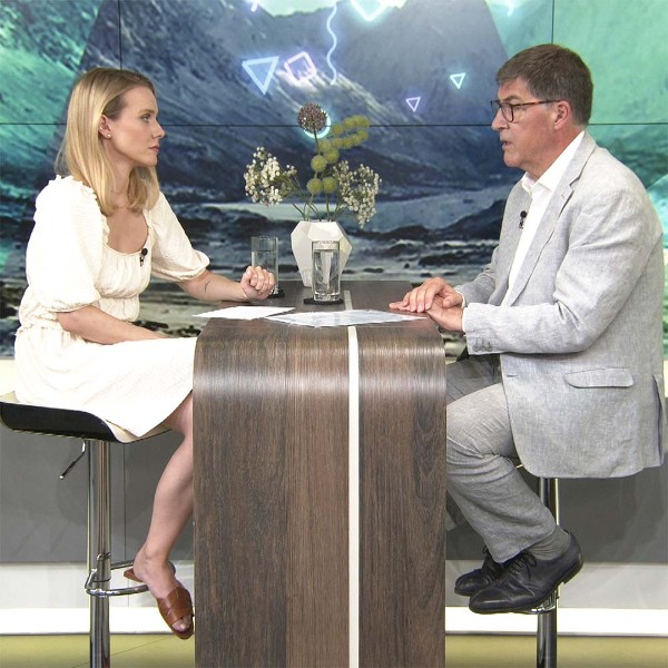 Die Moderatorin von krone.tv, Raphaela Scharf, und der Chefarzt der &Ouml;sterreichischen Gesundheitskasse, Dr. Andreas Krauter, sitzen einander im Studio an einem Pult gegen&uuml;ber.